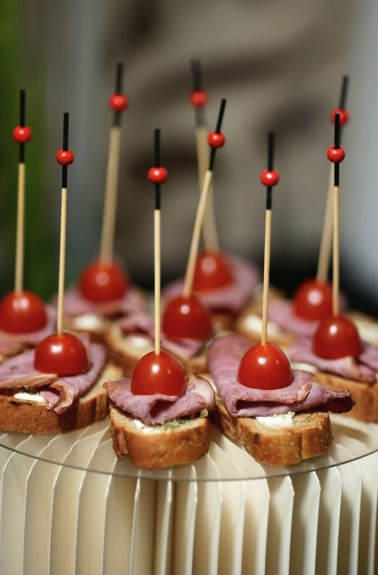 Bruschetta canapés topped with cured beef and cherry tomatoes on skewers