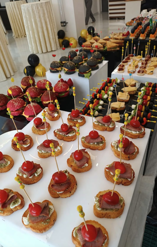 Corporate canapé buffet with mini burgers and skewers on white risers
