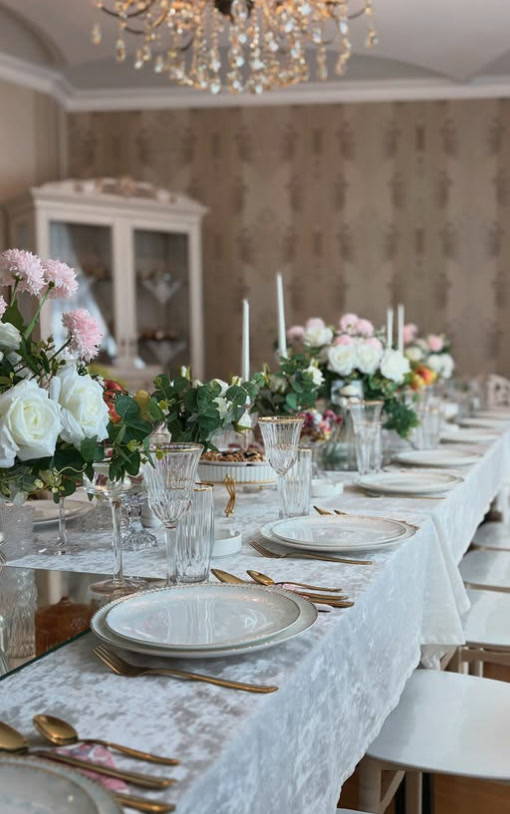 Private dining room with a chandelier and a long table set in white and gold